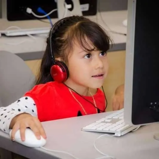 A young student wearing headphones using a computer